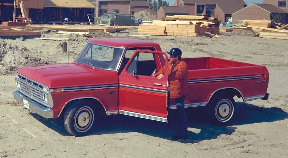 A red 1976 Ford F-150, which is a classic among used Ford trucks, is parked at a construction site.