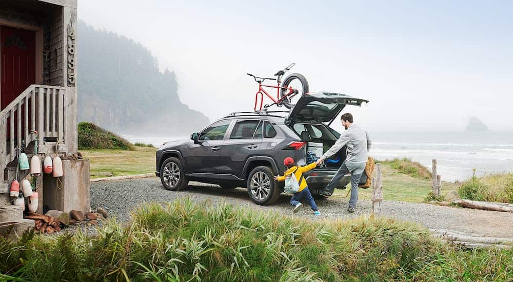 A father and son are unloading a grey 2020 Toyota RAV4 on foggy beach. 