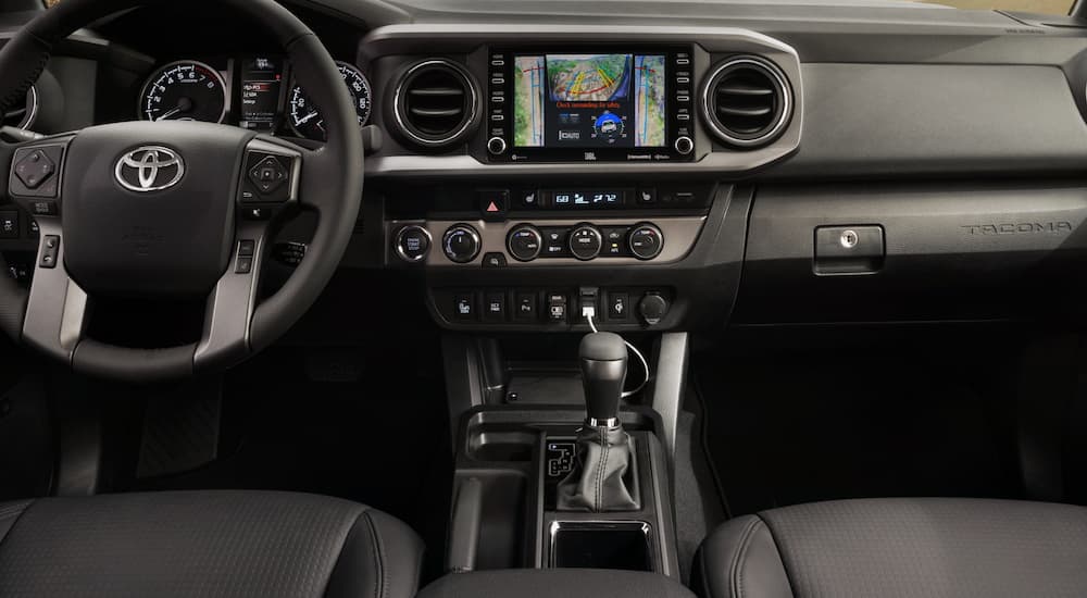 The black interior of a 2020 Toyota Tacoma is shown featuring the infotainment screen.