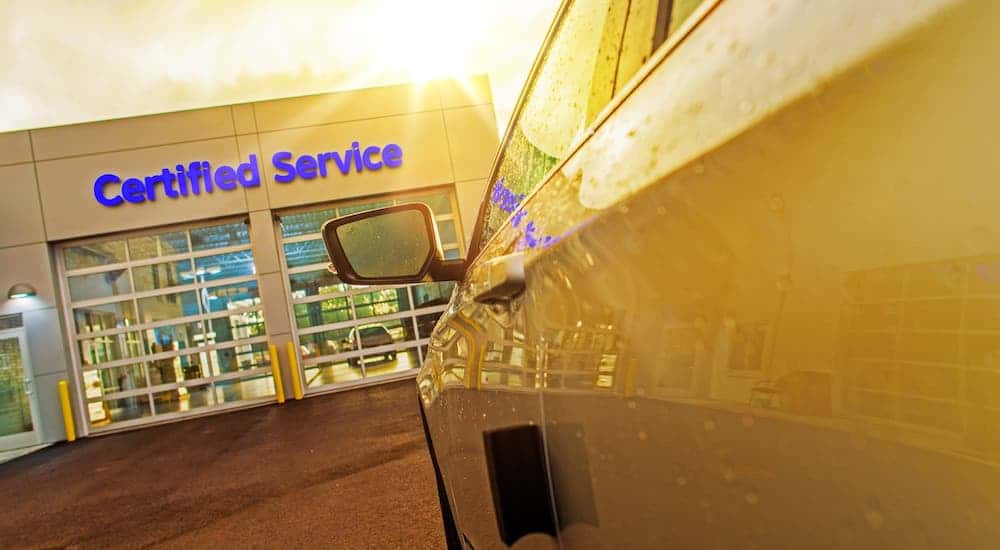 A low angle is shown of a car in front of a Chevy dealership garage with "Certified Service" written above the door.
