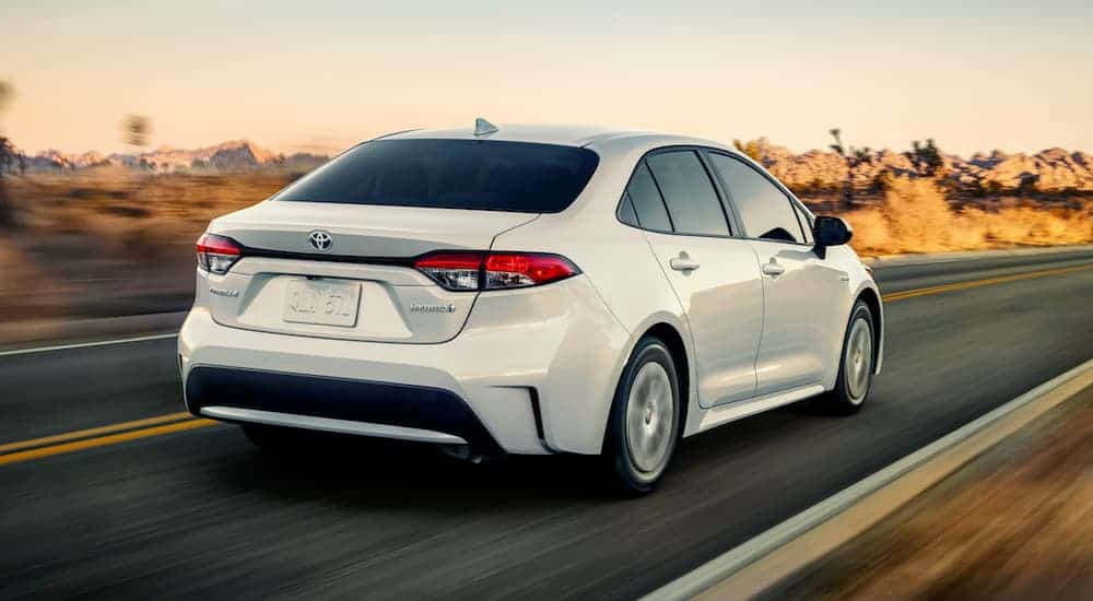 A white 2020 Toyota Corolla is driving at sun down in the desert.