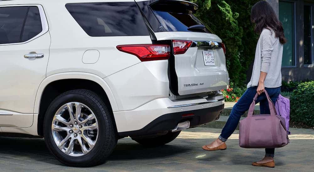 A woman with bags in her arms is using the hands free liftgate on her 2019 Chevy Traverse, which is a popular feature on used cars for sale.