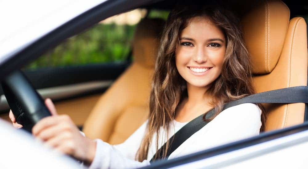 A young woman is sitting in the driver's seat taking a white car for a test drive.