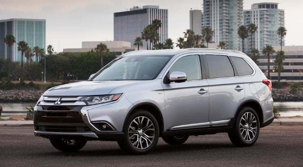 A silver 2017 Mitsubishi Outlander is parked in front of a city sky line.