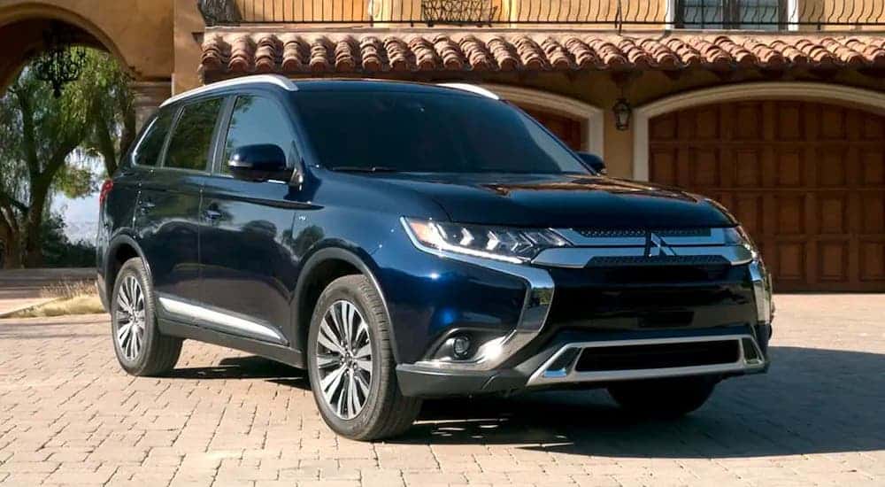 A black 2019 Mitsubishi Outlander from a used car dealership near me is parked in front of a garage.