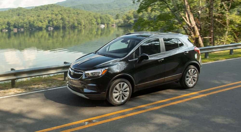 A black 2020 Buick Encore is driving past a lake.