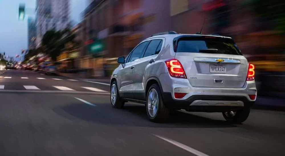 A white 2020 Chevy Trax is driving down a city street at night.