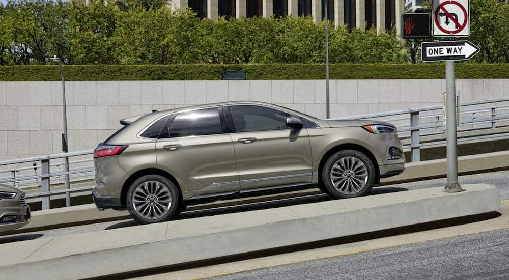 A gold 2020 Ford Edge is stopped at a light on an incline in a city.