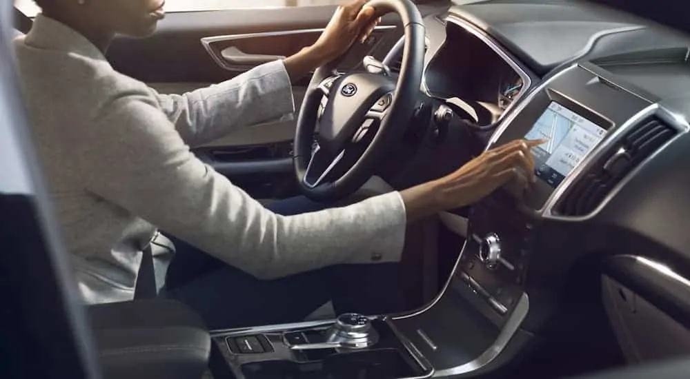 A woman is using the touchscreen inside a 2020 Ford Edge.