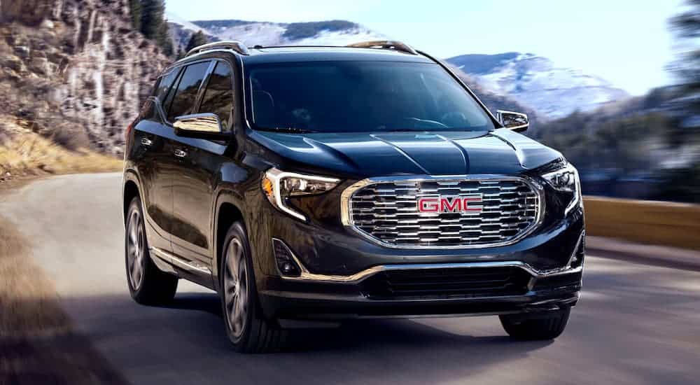 A black 2020 GMC Terrain is driving on a mountain road.
