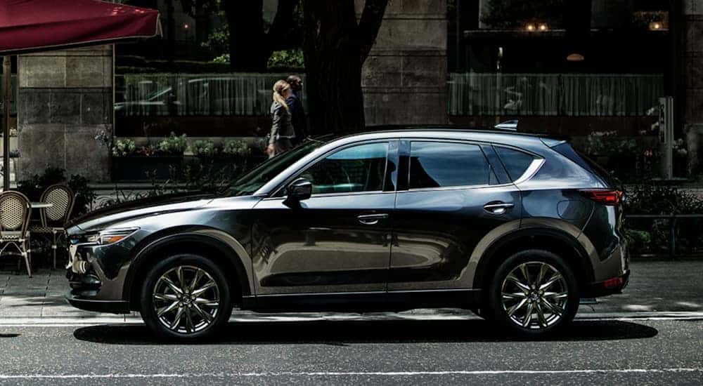 A dark grey 2020 Mazda CX-5 is shown from the side on a city street.