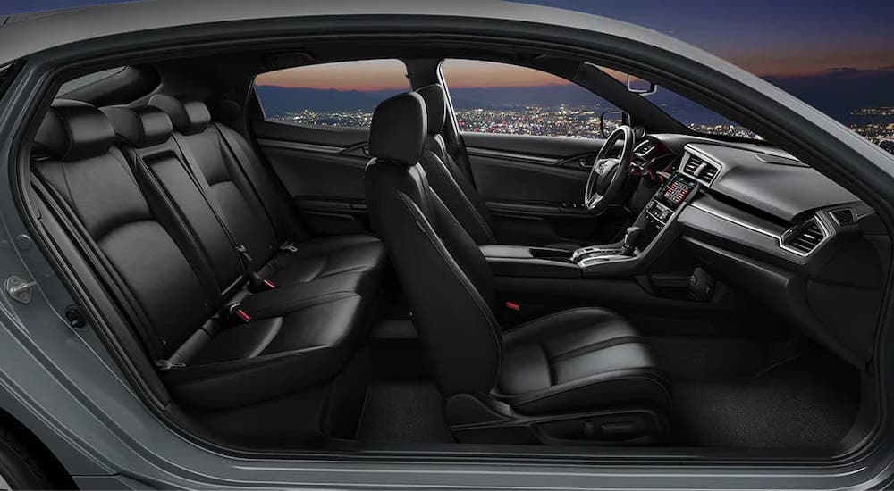 The two rows of seats in a 2020 Honda Civic Hatchback Sport Touring are shown from the side at dusk.