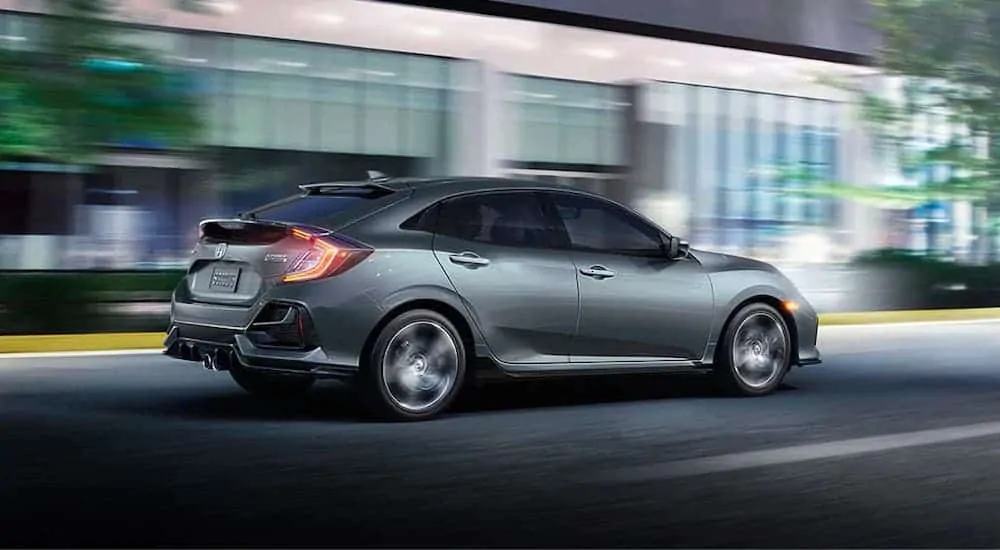 A gray 2020 Honda Civic Hatchback Sport Touring races down a city street at night.