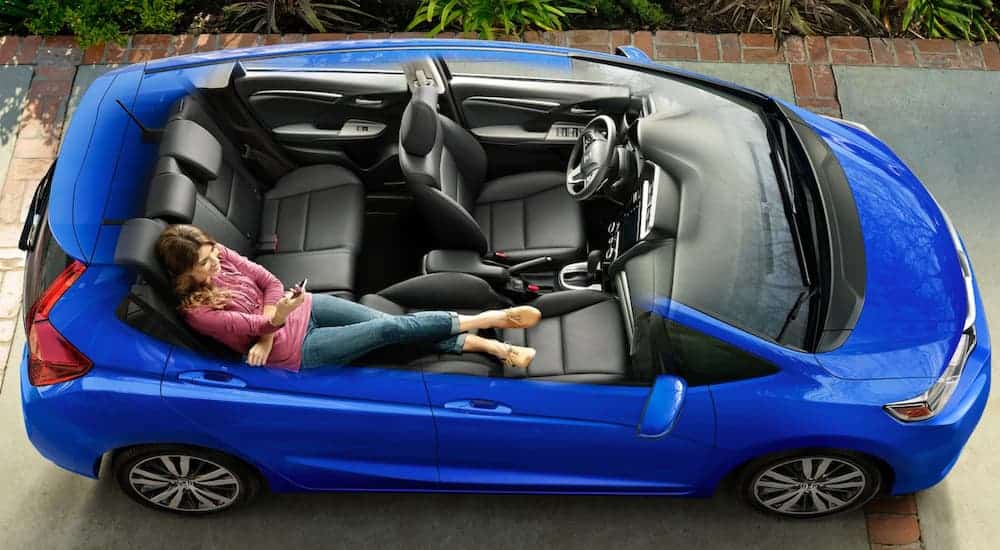 A blue 2020 Honda Fit is shown cut away to show a woman lounging across the back and front seat.