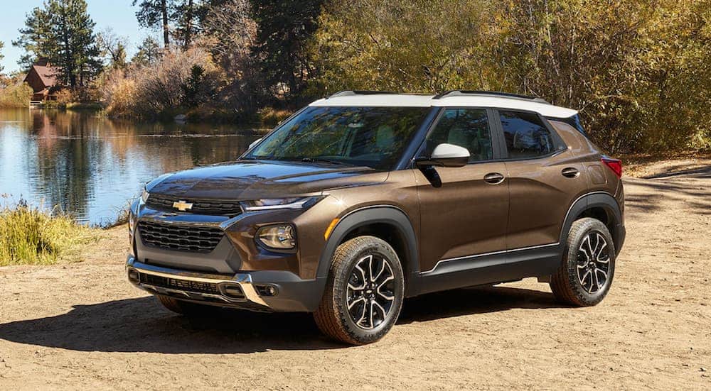 A brown and white 2021 Chevy Trailblazer, which wins when comparing the 2021 Chevy Trailblazer vs 2020 Nissan Kicks, is parked at a pond.