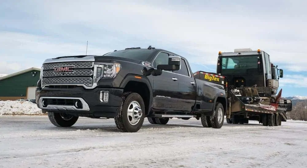 A low angle is shown of a black 2020 GMC Sierra 3500HD Denali that is towing construction equipment.