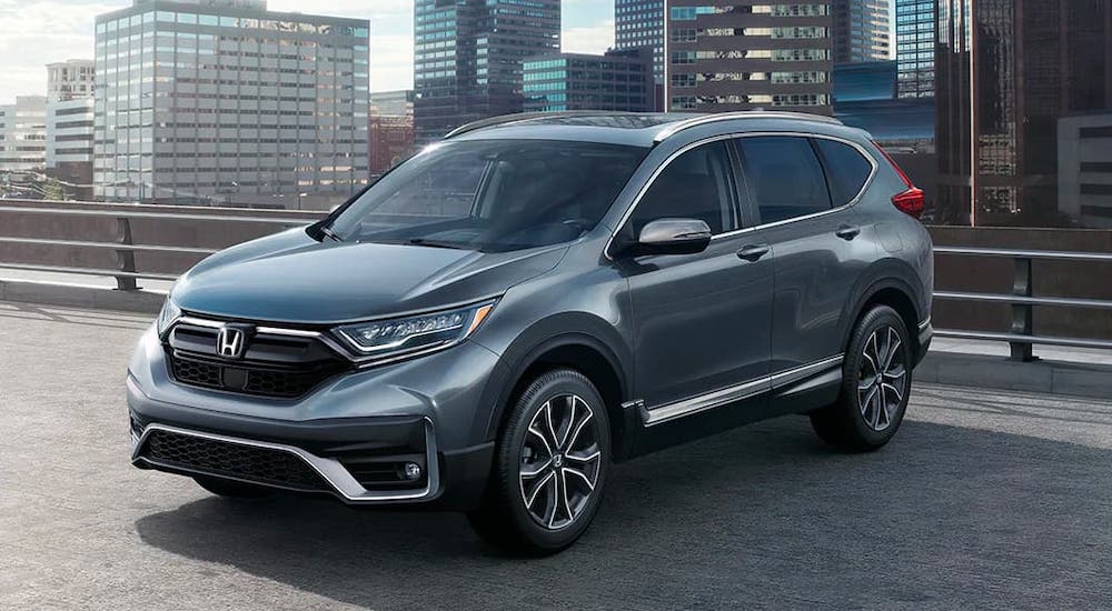 A gray 2020 Honda CR-V Touring is parked atop a parking garage. Check one out at a Honda Dealer Near Me.