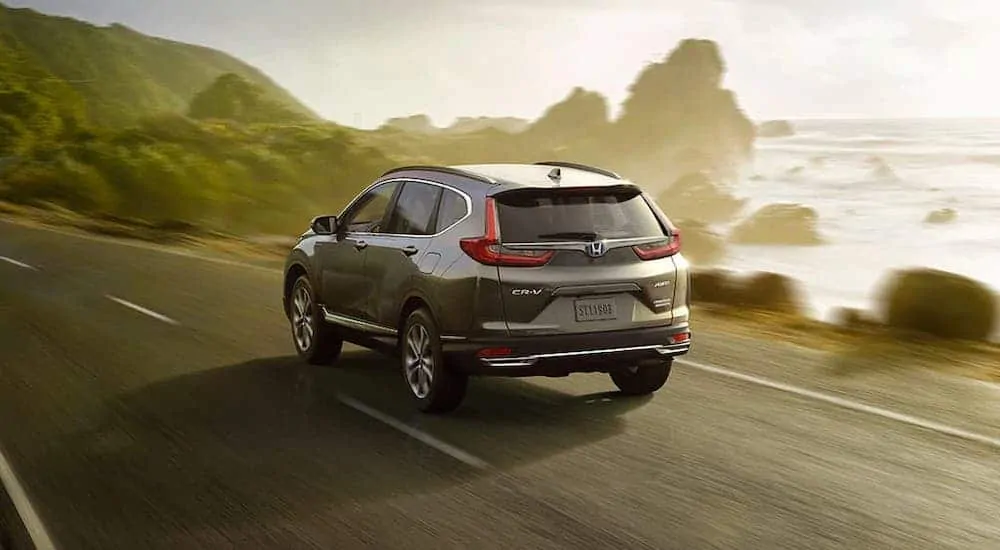 A gray 2020 Honda CR-V Hybrid Touring is driving along the coast.