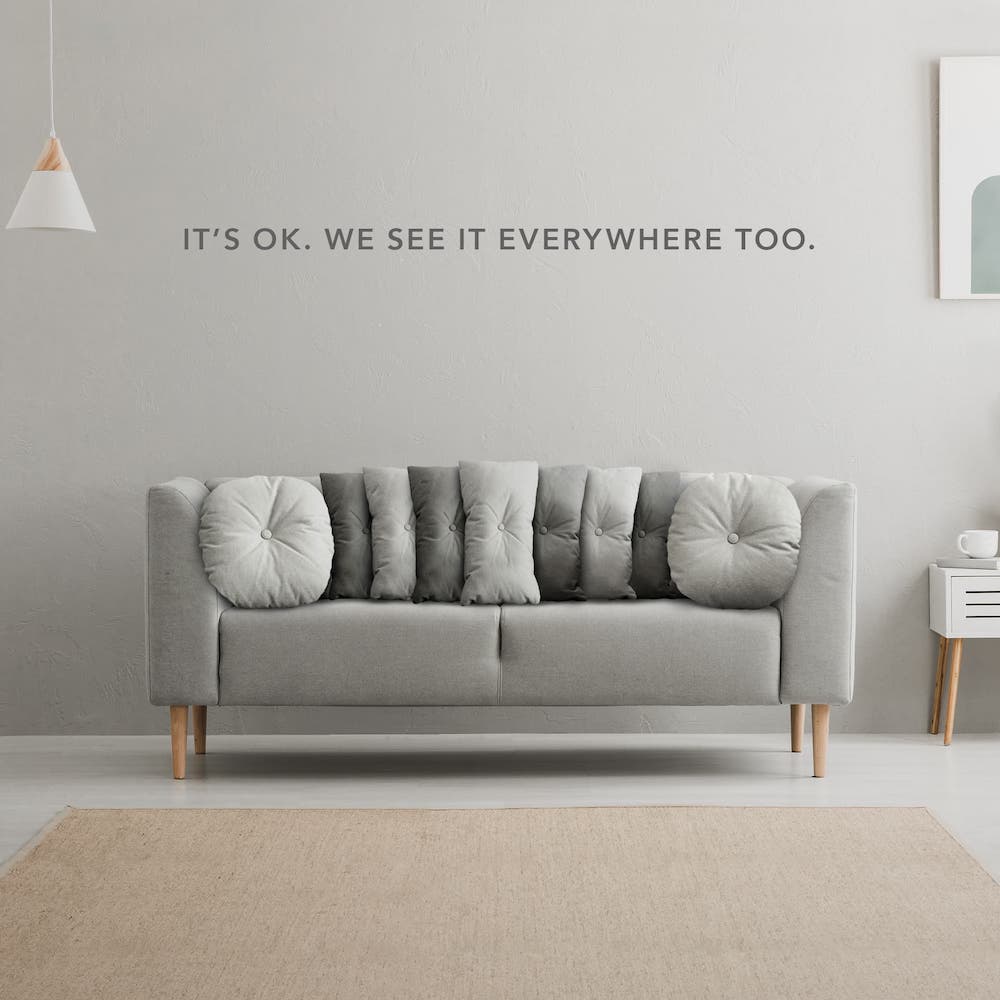 A gray couch has pillows on it that resemble the grille of a Jeep with the text "It's OK. We see it everywhere too."
