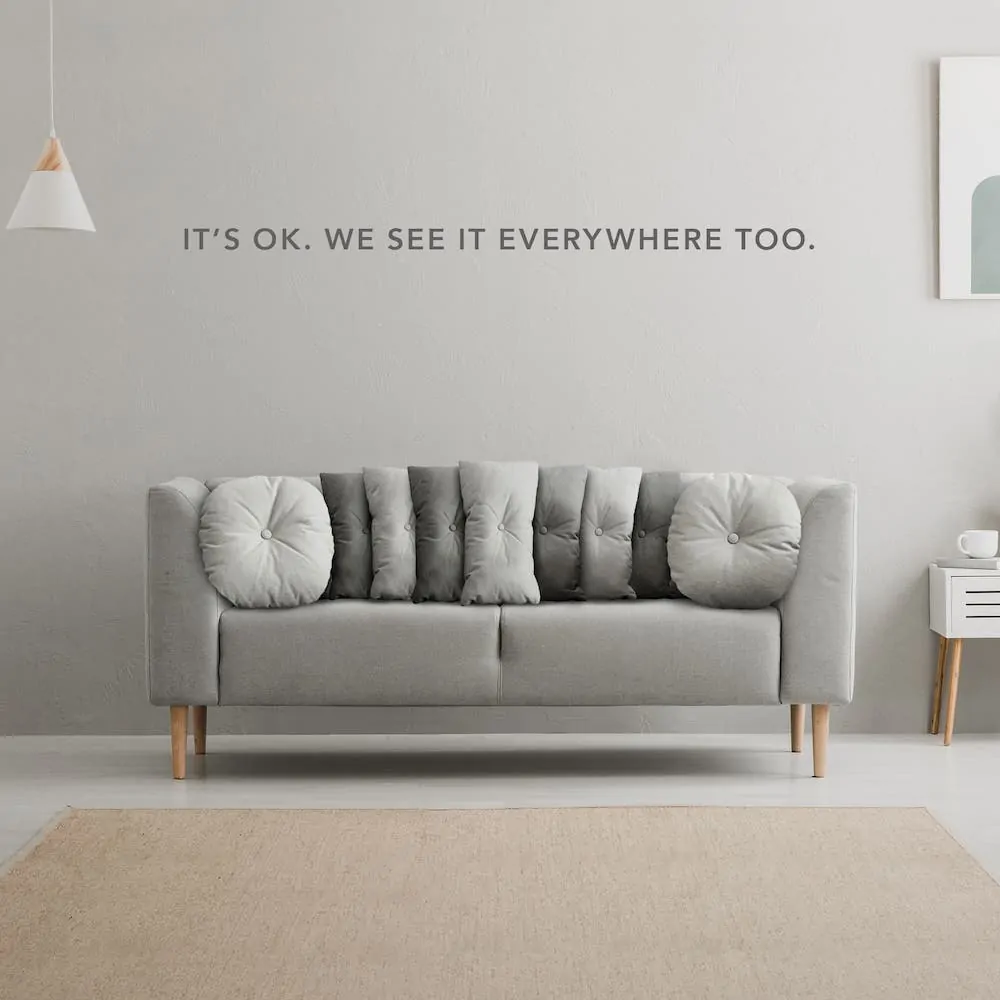 A gray couch has pillows on it that resemble the grille of a Jeep with the text "It's OK. We see it everywhere too."