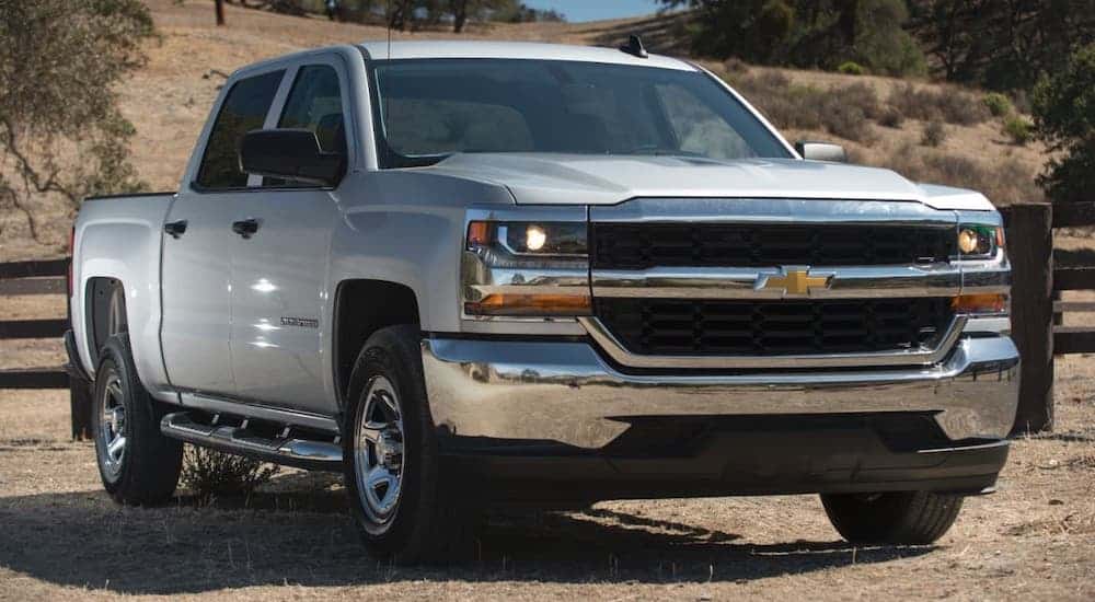 One of the popular used trucks, a silver 2017 Chevy Silverado 1500, is parked in front of a ranch.