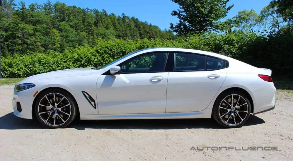 A white 2020 BMW 840i Gran Coupe is shown from the side in a dirt parking lot.