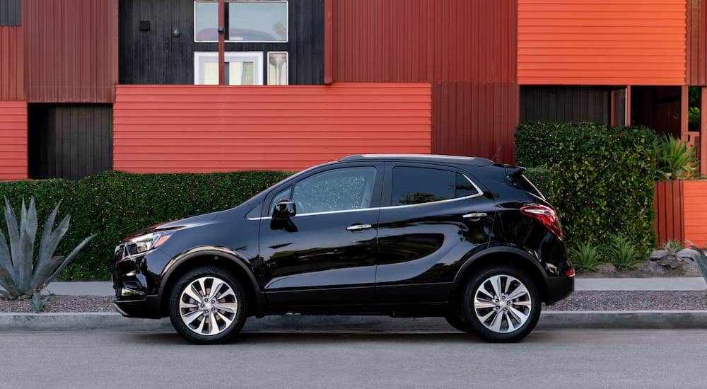 A black 2020 Buick Encore is parked in front a building with red metal panels.