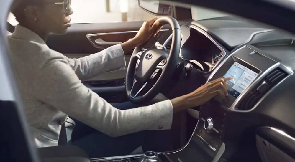 A woman is using the touch screen in a 2020 Ford Edge.