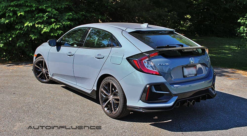 A blue 2020 Honda Civic Hatchback is shown from the rear in front of trees.