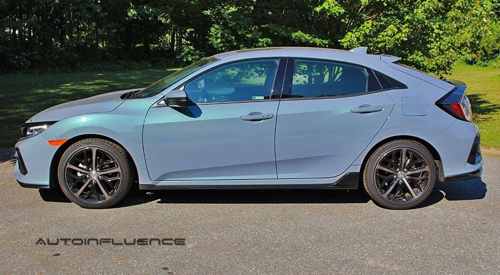 A blue 2020 Honda Civic Hatchback is sown from the side in front of trees.