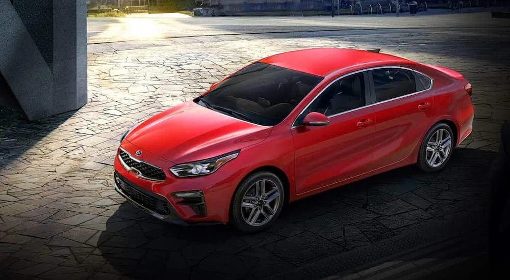 A red 2020 Kia Forte is parked on stone pavers.