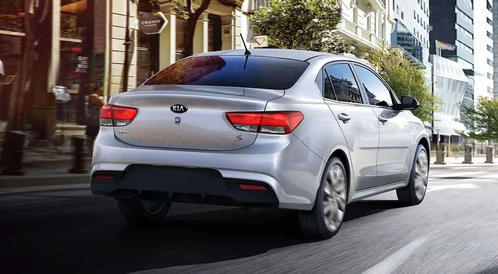 A silver 2020 Kia Rio is driving away on a city street.