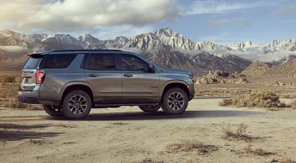 A gray 2021 Chevy Tahoe is parked in a desert with mountains in the distance. You'll likely see this version at your local Chevy dealership instead of the PPV.