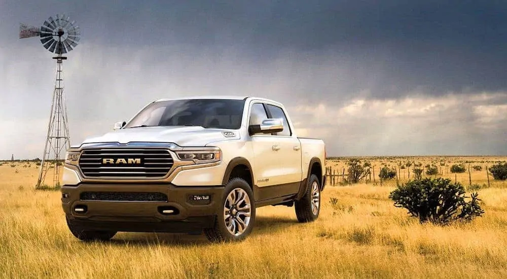 A white 2020 Ram 1500 Laramie Longhorn is parked in front of a field and windmill.