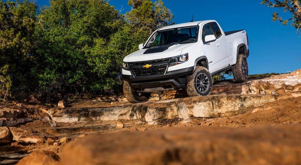 A white 2020 Chevy Colorado is driving over rocks.