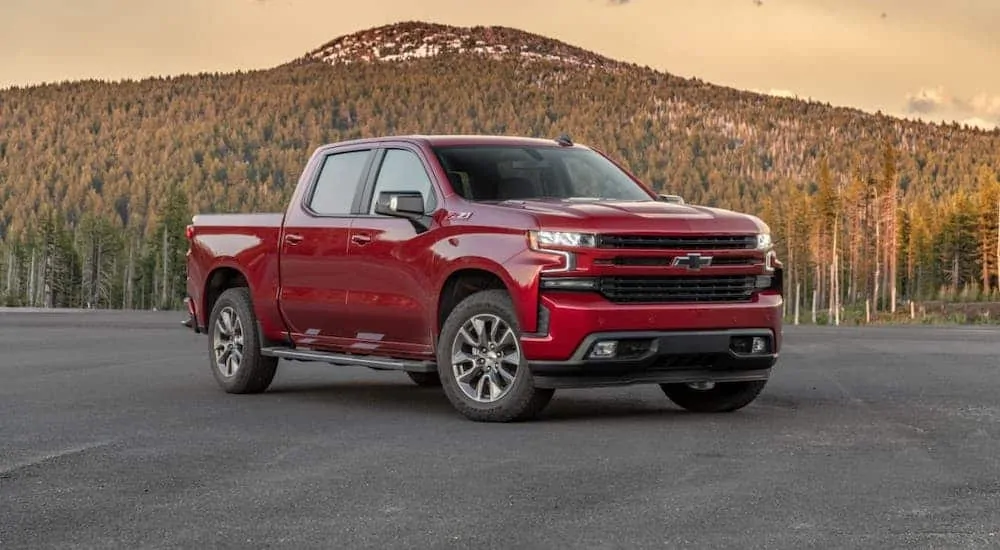 A red 2020 Chevy Silverado truck for sale is parked in a lot in front of a mountain.