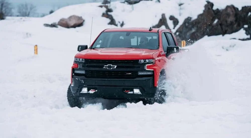A popular truck for sale, a red 2020 Chevy Silverado 1500 TrailBoss is kicking up snow in the mountains.