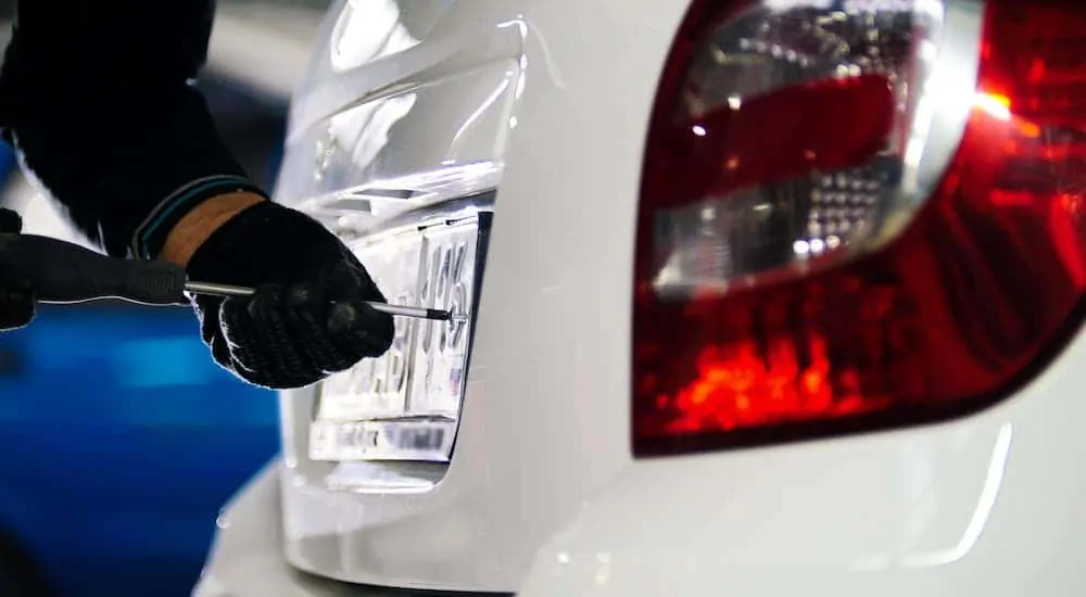 A license plate is being changed on a white car at a Used Car Dealership Near Me.