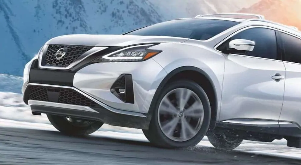 A white 2020 Nissan Murano is shown driving on a snowy road.