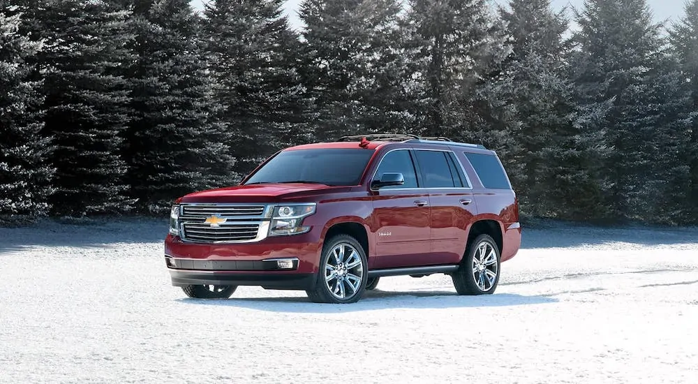 A red 2020 Chevy Tahoe is parked in a snowy field in front of evergreen trees after winning the 2020 Chevy Tahoe vs 2020 Toyota Sequoia comparison.
