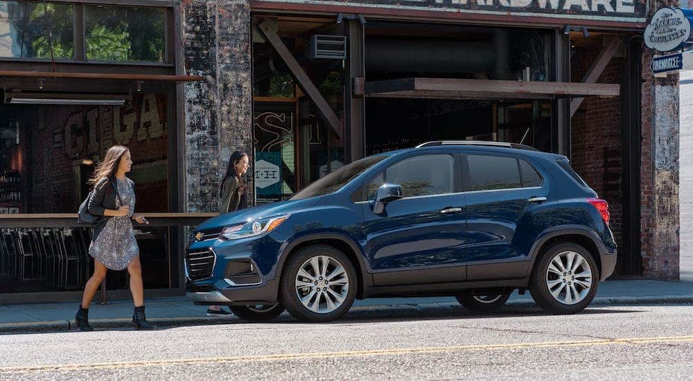 Two women are walking towards a blue 2020 Chevy Trax which is parked on a city street.