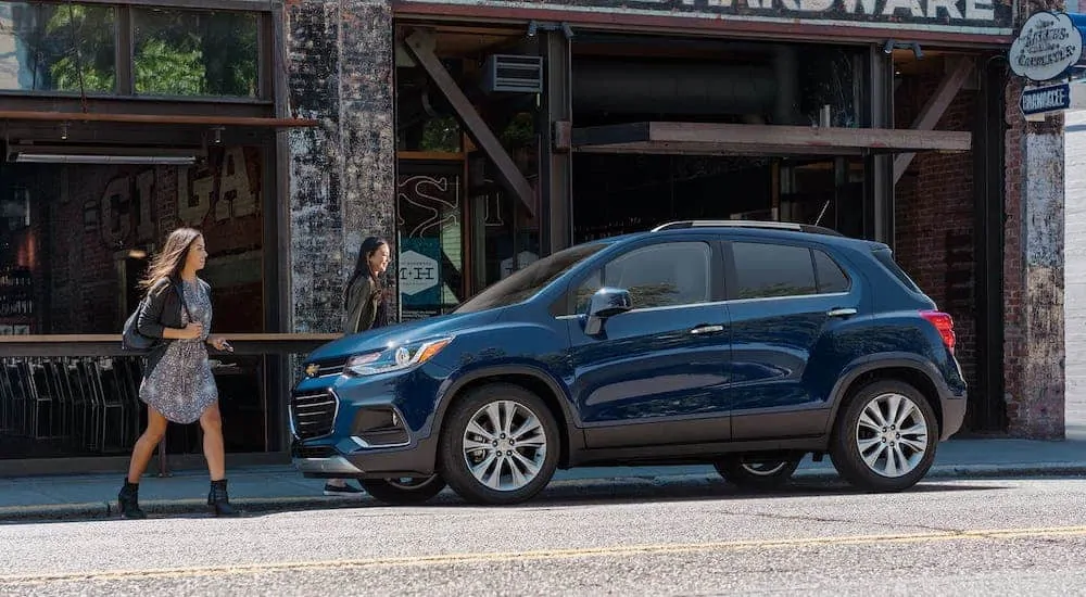 Two women are walking towards a blue 2020 Chevy Trax which is parked on a city street.