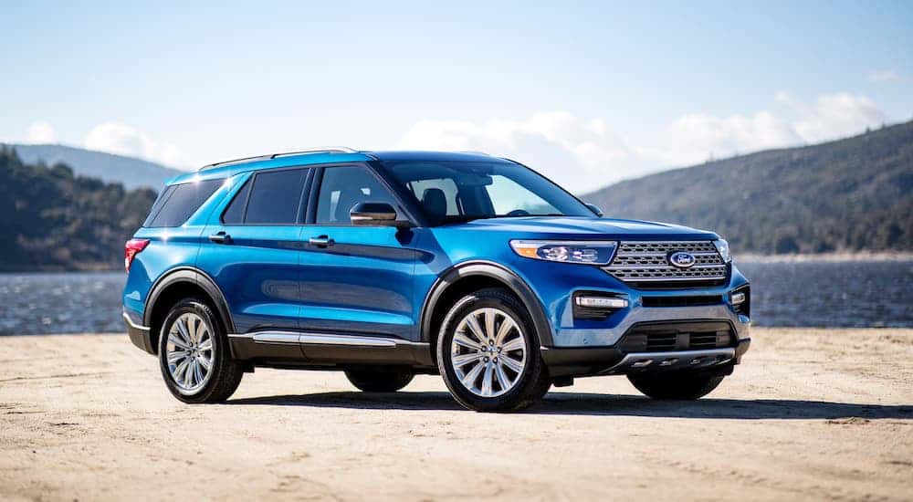 A blue 2020 Ford Explorer ST is parked in front of a lake.