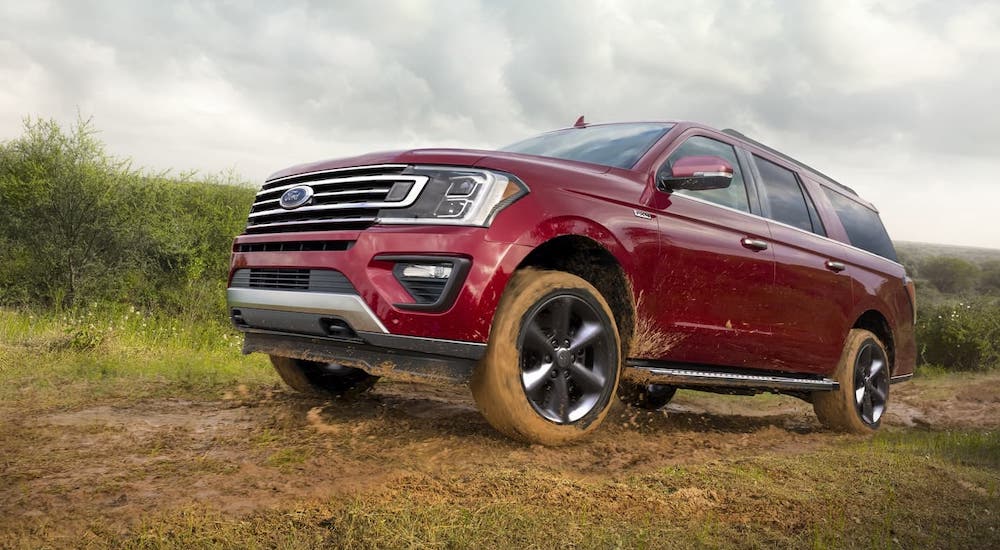 A red 2020 Ford Expedition XLT is driving through mud after winning the 2020 Ford Expedition vs 2020 Nissan Armada competition.