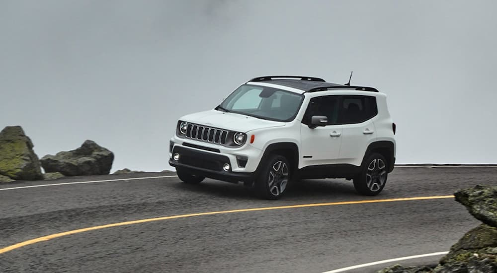 A white 2020 Jeep Renegade is driving around a very foggy corner.