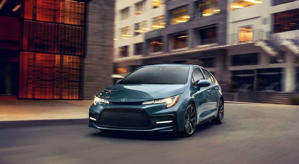 A blue 2020 Toyota Corolla is driving around a corner in a city.