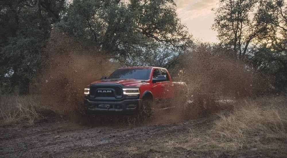 A red 2020 Ram 2500 Power Wagon is kicking up mud on a trail.