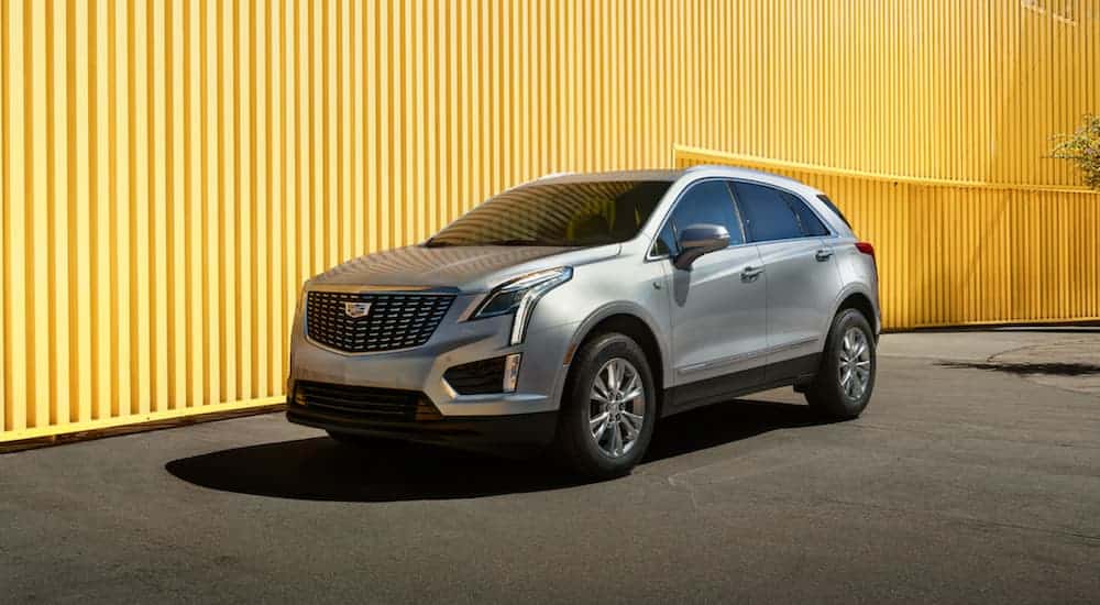 A silver 2020 Cadillac XT5, which is popular among Cadillac SUV models, is in front of a yellow wall.