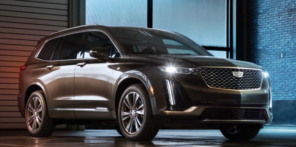 A grey 2020 Cadillac XT6 is parked in a dark warehouse.