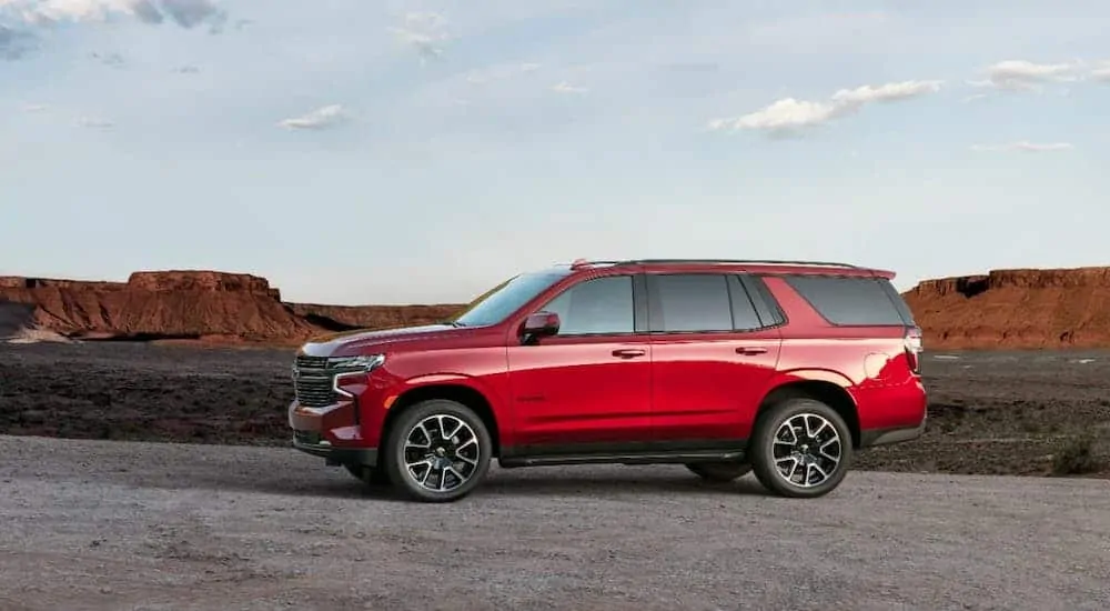 A new Chevy SUV, a red 2021 Chevy Tahoe RST is parked in front of an empty desert.